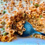 baked pasta rings with sauce and cheese in a white casserole dish