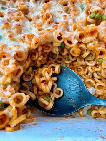 baked pasta rings with sauce and cheese in a white casserole dish