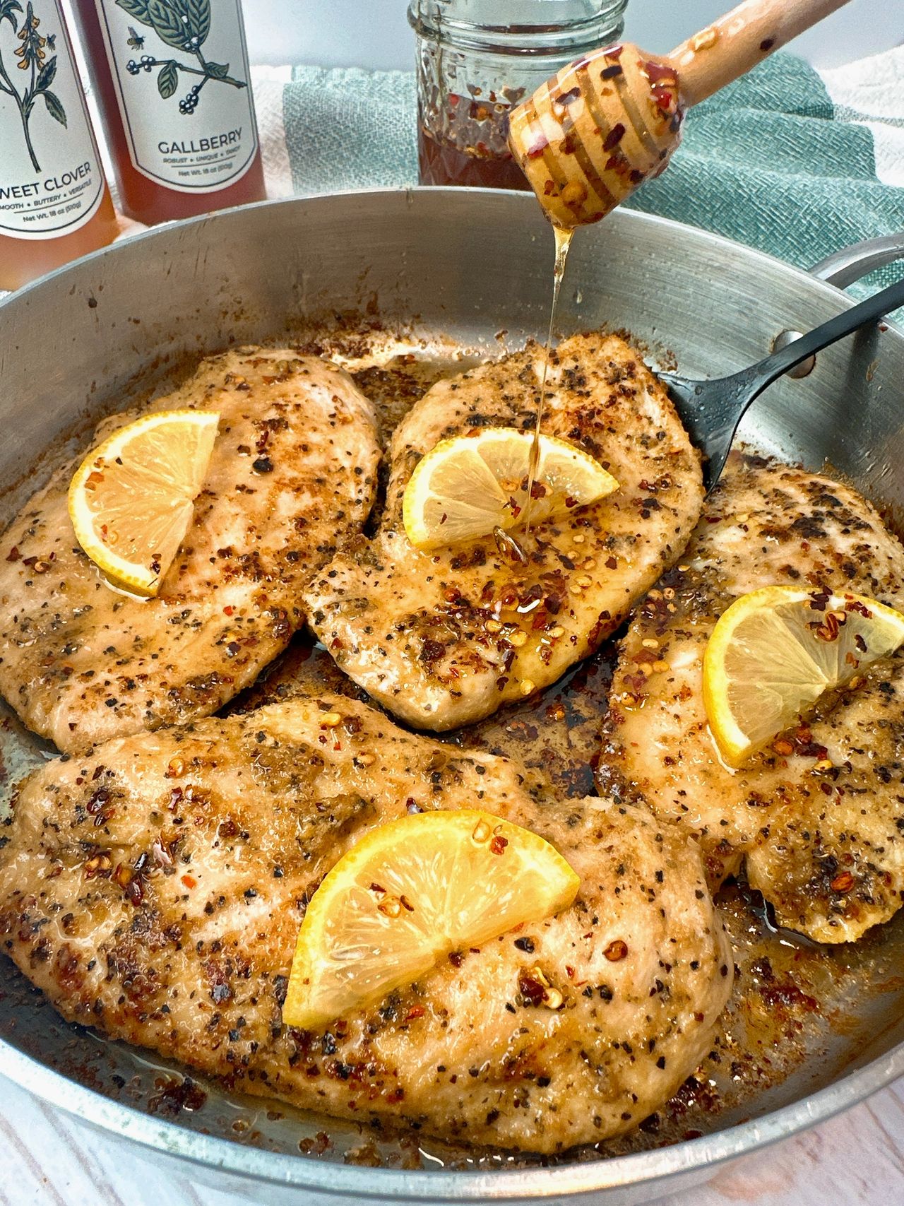 chicken and lemon in a skillet with a drizzle of honey