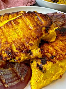 saffron chicken and red onion on a white plate