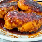 hot honey chicken in a white skillet with a black spoon