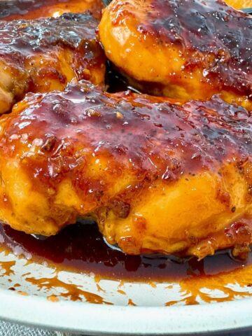 hot honey chicken in a white skillet with a black spoon