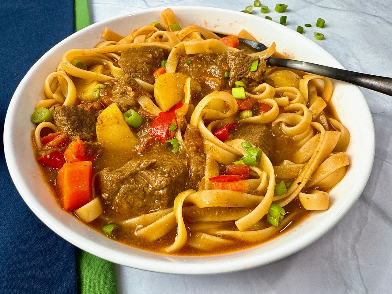 beef and noodle stir fry in a white bowl