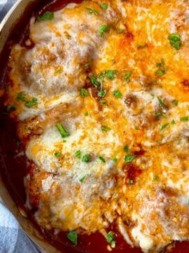 chicken thighs and marinara sauce with cheese in a pan