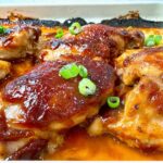 Chicken thighs on a baking sheet with a teriyaki glaze.