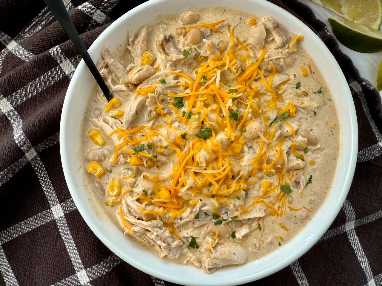 white chicken chili in a white bowl on a brown kitchen towel