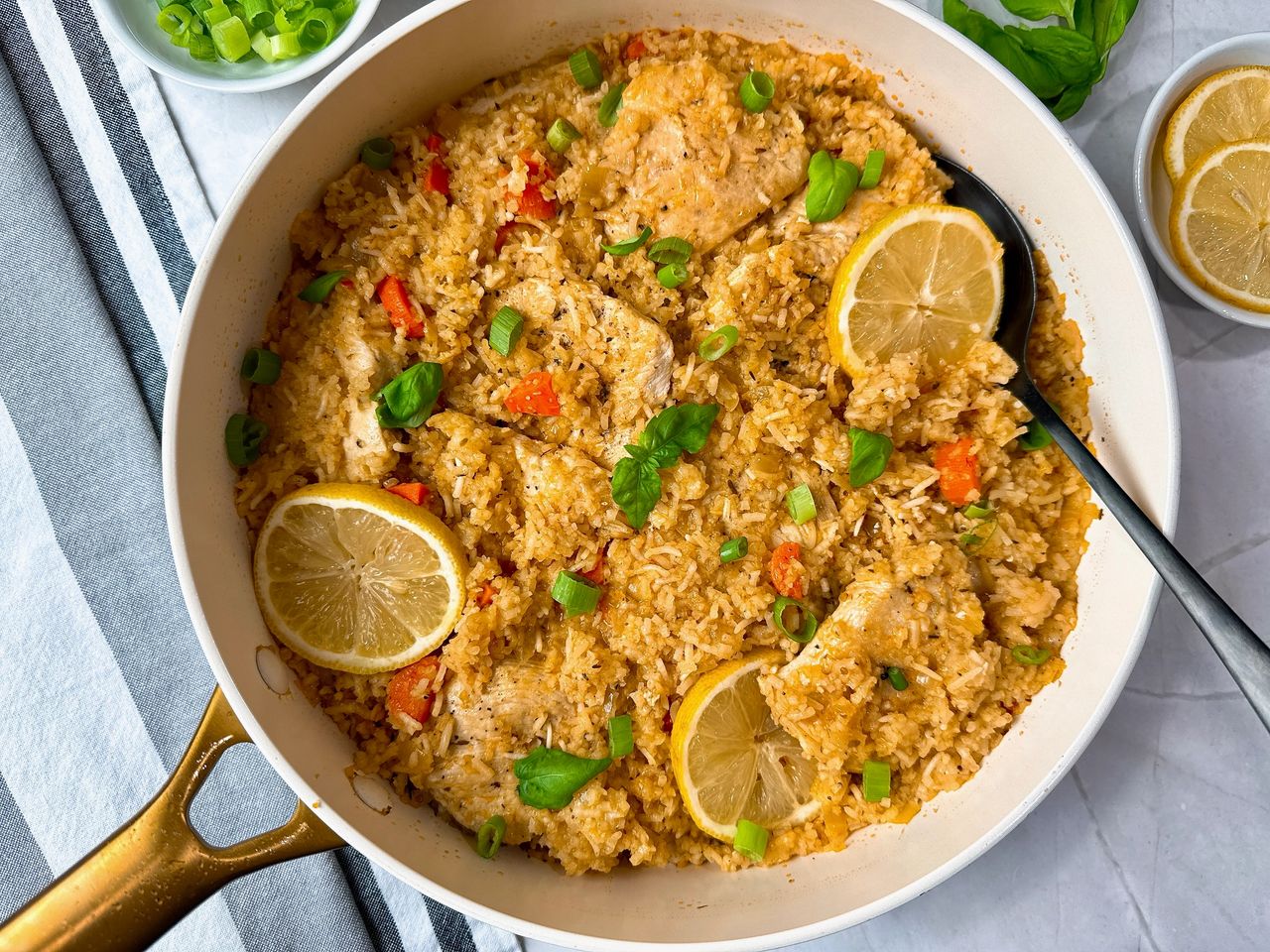 chicken and rice in a white saucepan with lemon garnish