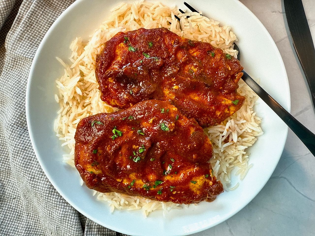 chicken with enchilada sauce over rice on a white plate
