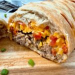 breakfast braid with eggs, cheese and sausage on a wooden cutting board