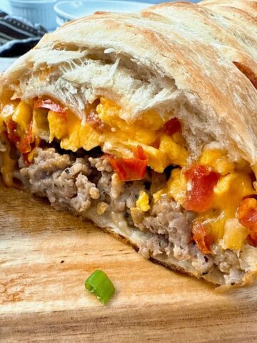 breakfast braid with eggs, cheese and sausage on a wooden cutting board