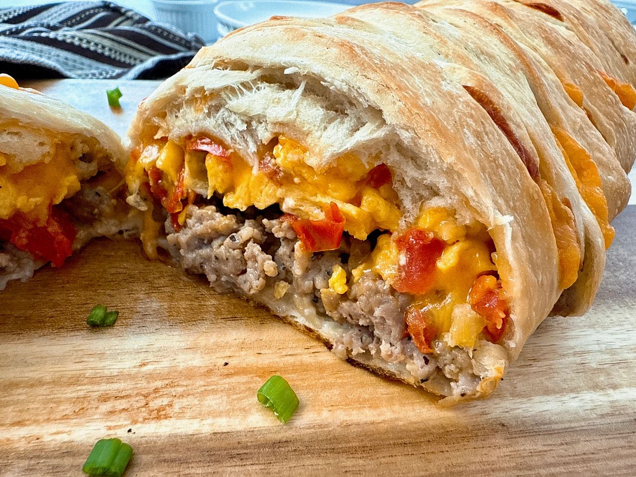 breakfast braid with eggs, cheese and sausage on a wooden cutting board
