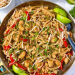 pad thai in a silver skillet with peanuts on the side