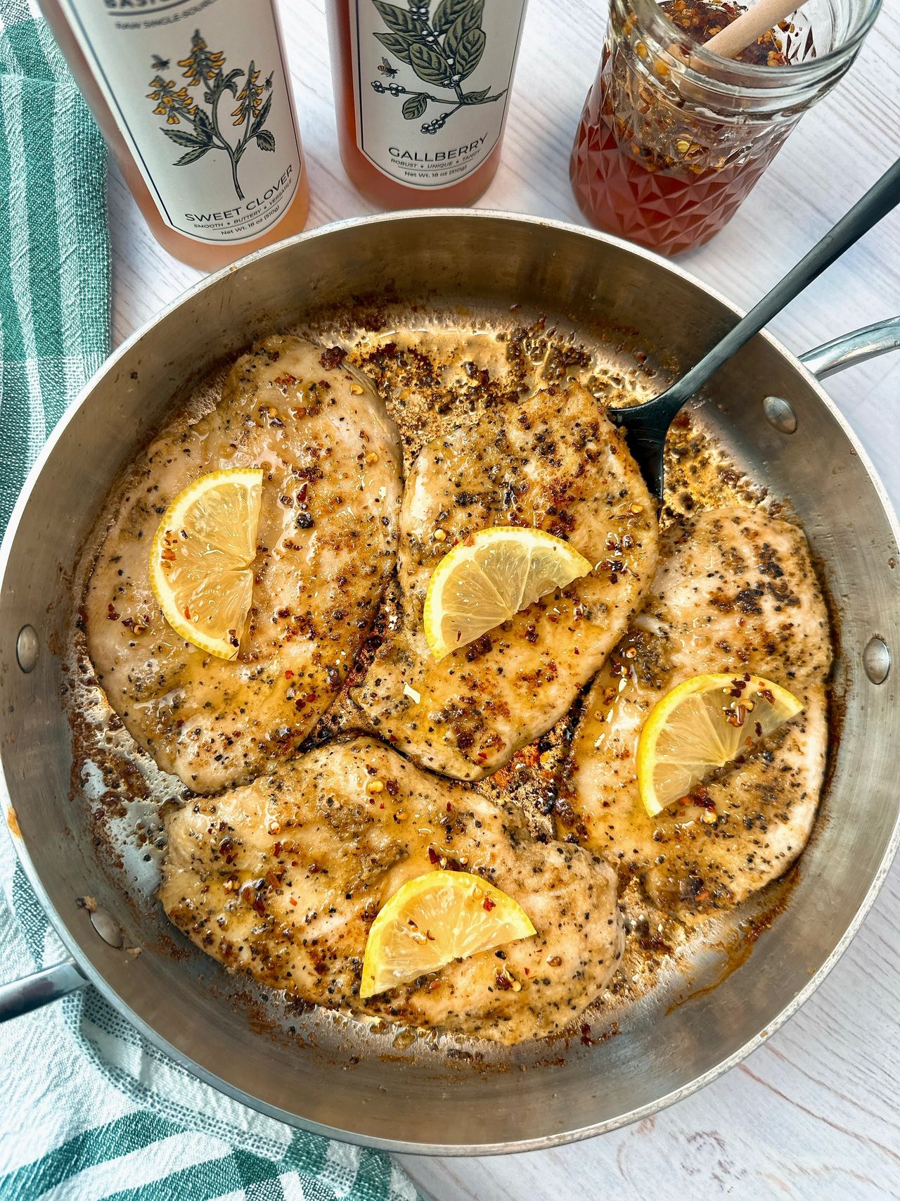 chicken and lemon in a skillet with a drizzle of honey