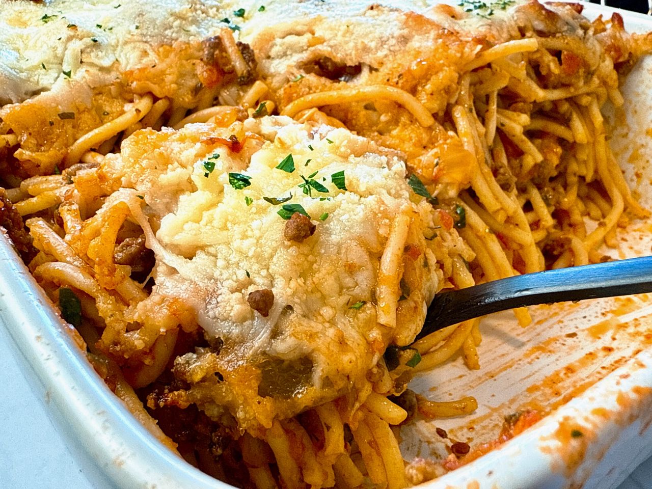 baked spaghetti in a baking dish with a black spoon
