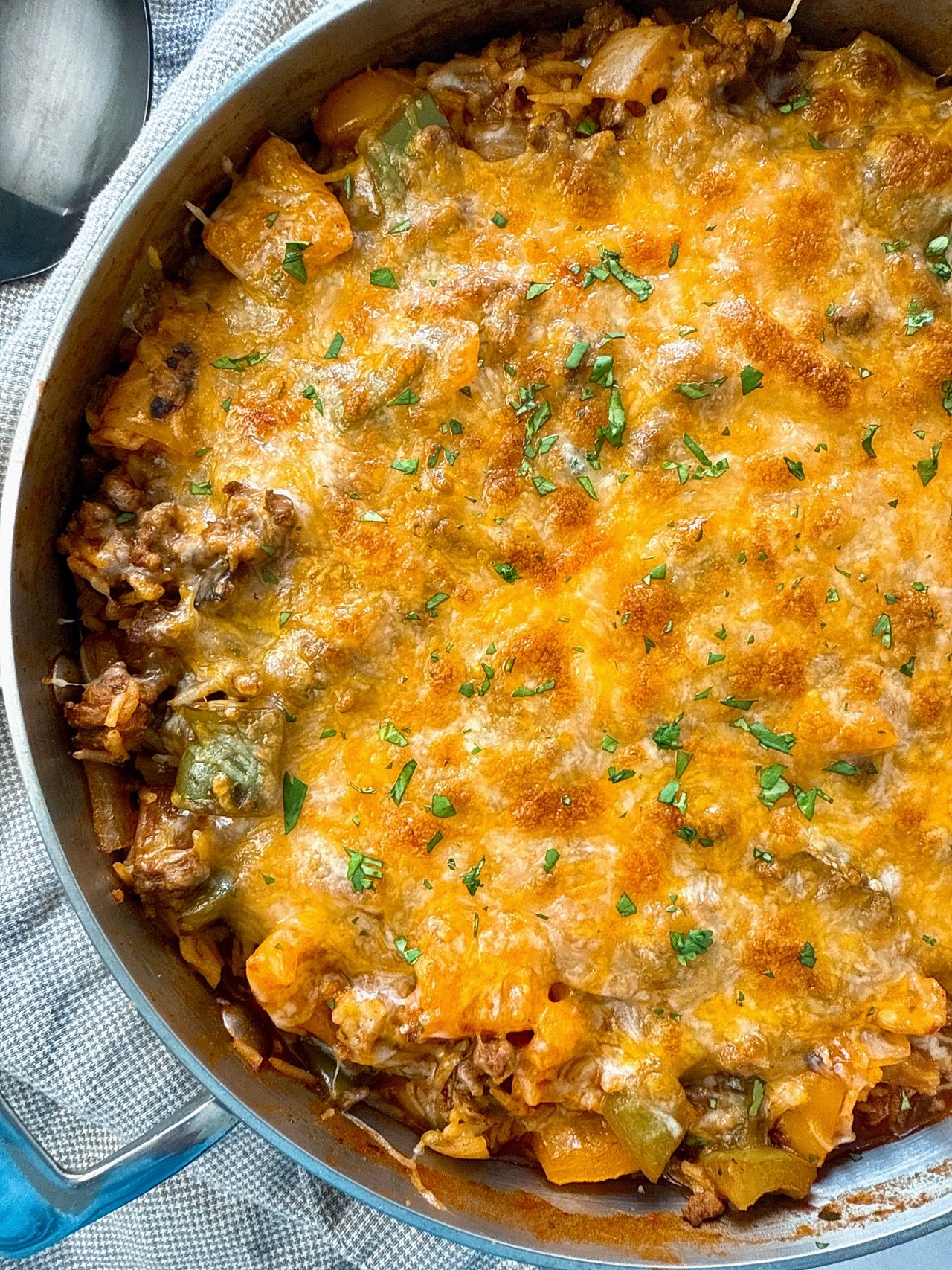 ground beef and rice covered with melted cheddar cheese in a deep skillet