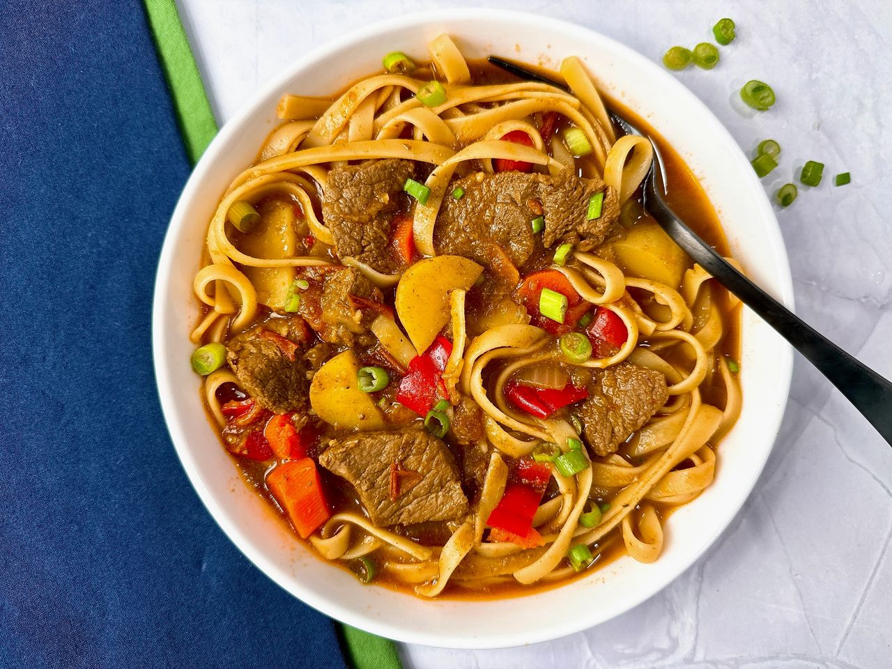 beef and noodle stir fry in a white bowl