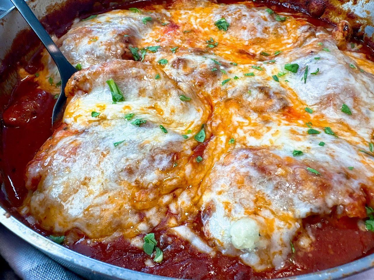 chicken thighs and marinara sauce with cheese in a pan