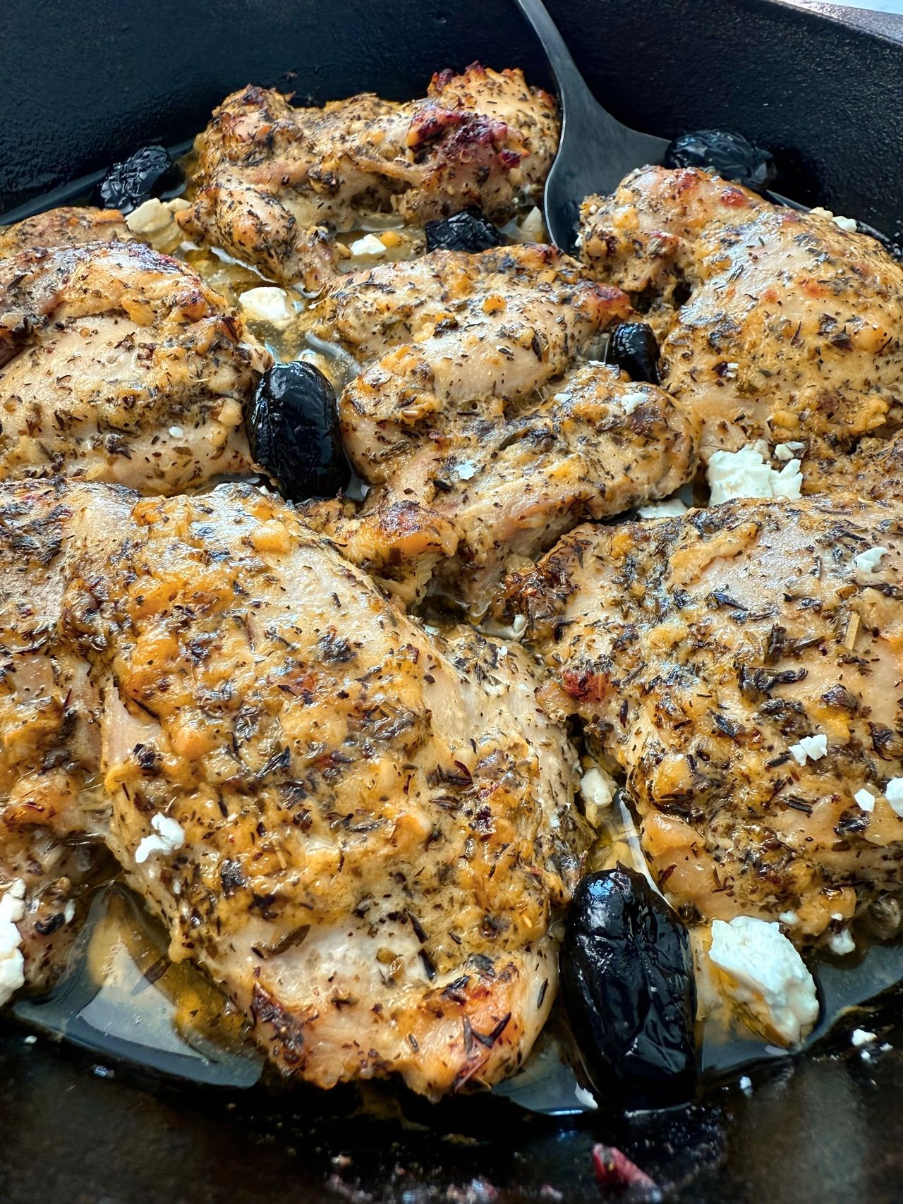 chicken thighs in a cast iron skillet with feta and olives
