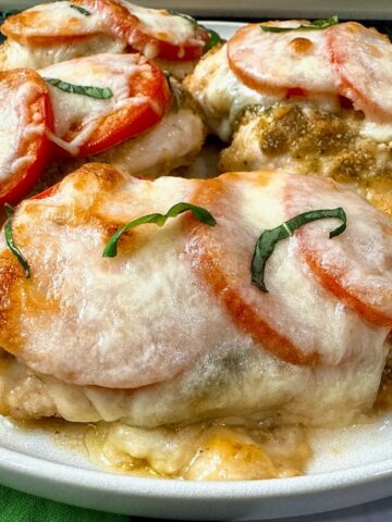baked chicken with cheese and tomatoes on a white plate