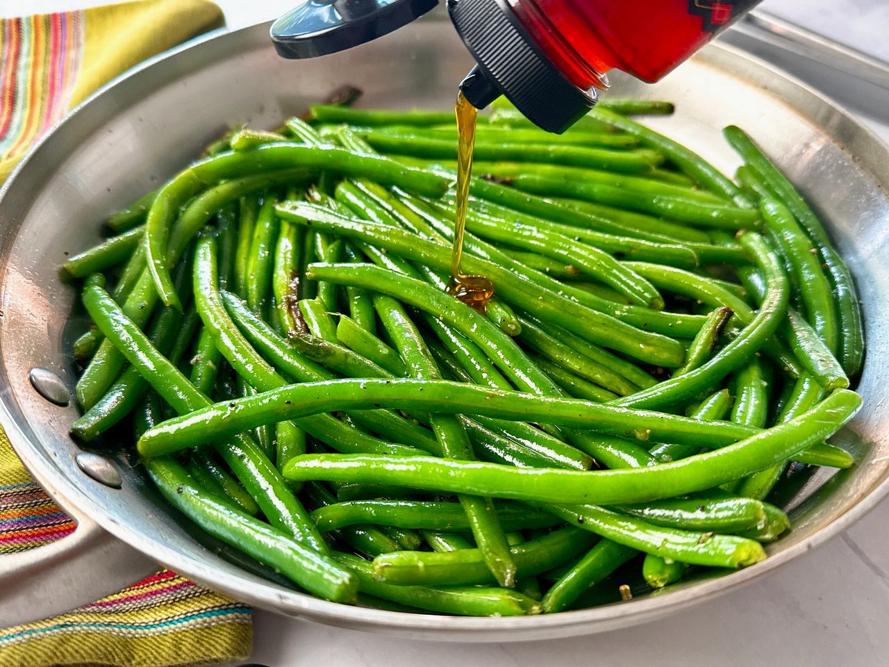 green beans in a skillet being drizzled with hot honey