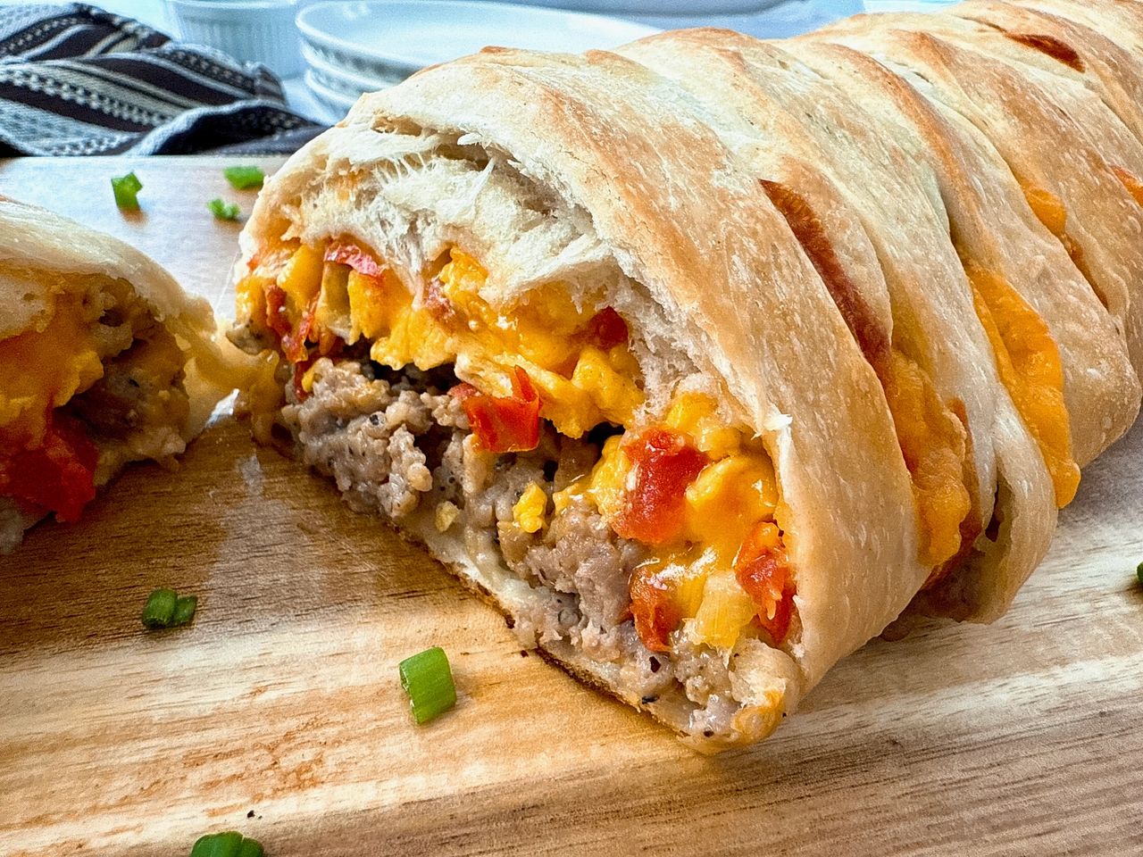 breakfast braid with eggs, cheese and sausage on a wooden cutting board