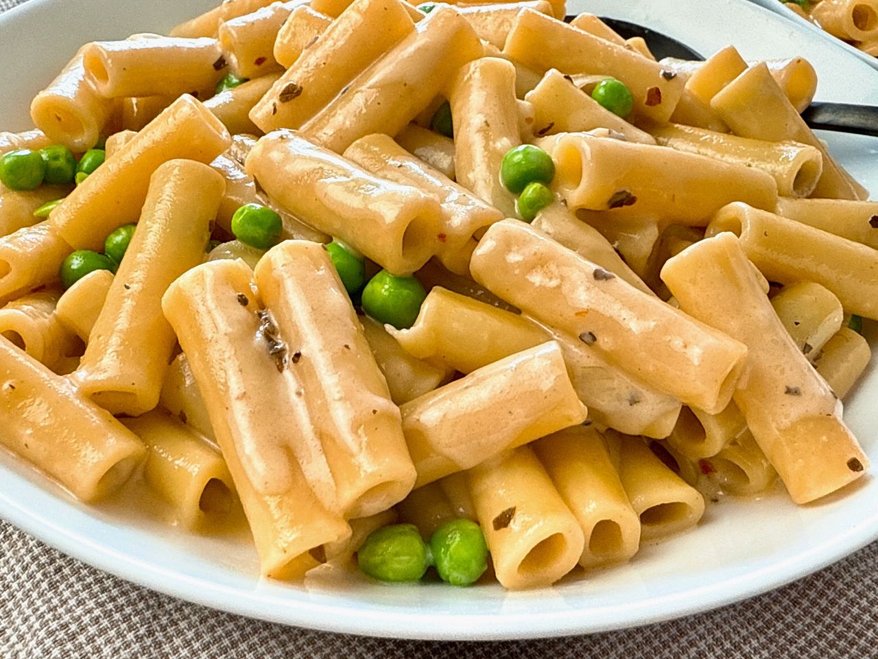 pasta and peas in a cream sauce in a white bowl