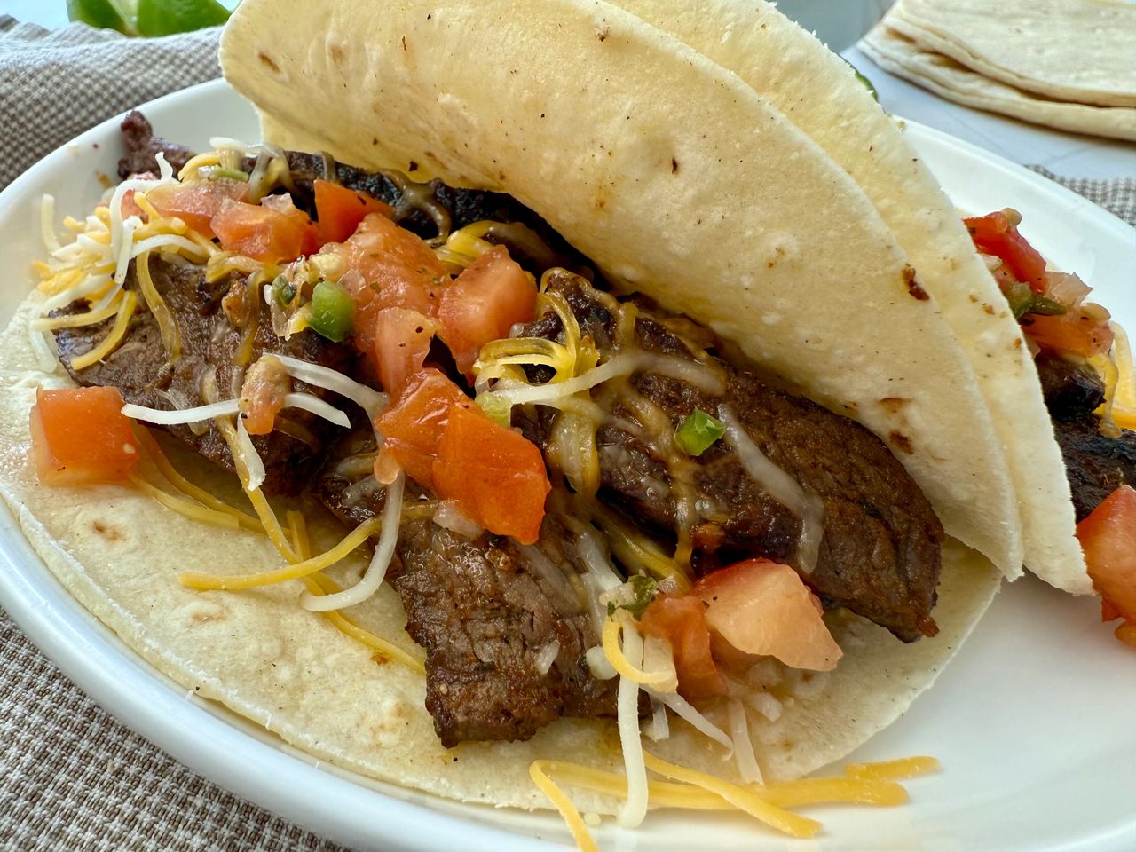 steak street tacos on a white plate with lime garnish