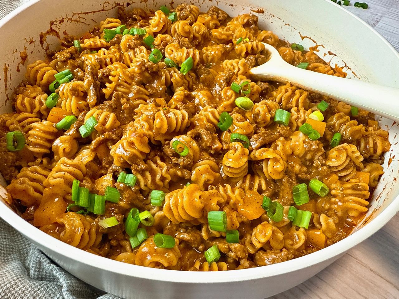 Beef Enchilada Pasta beef and pasta in an enchilada sauce in a white pan with a white spoon
