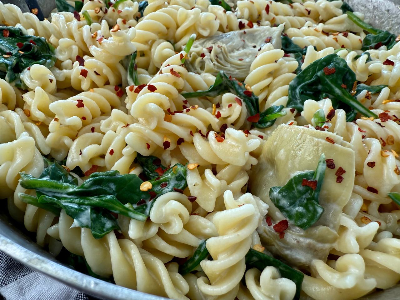 pasta with spinach and artichoke hearts in a skillet