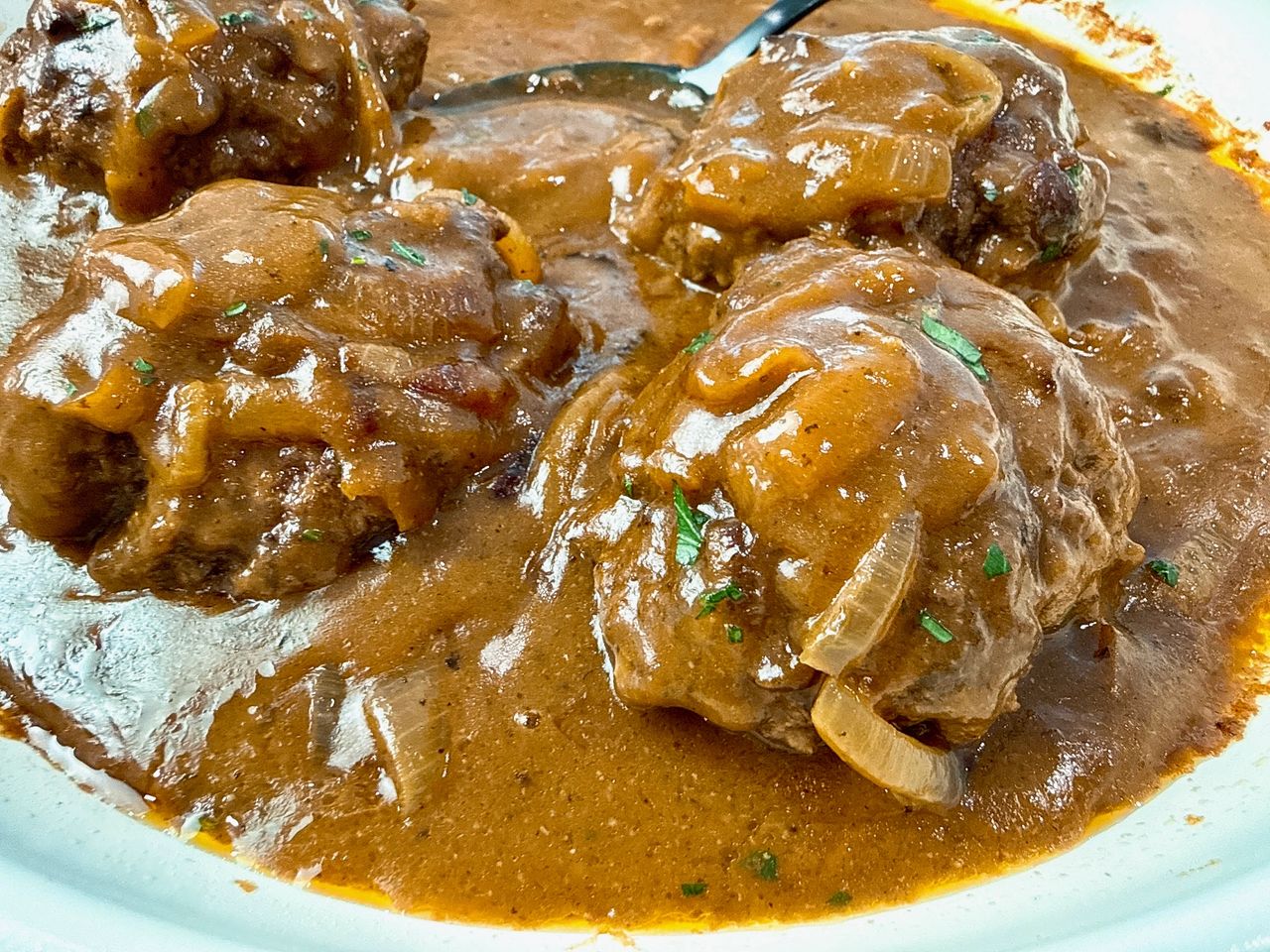 hamburger steaks and gravy with a black serving spoon