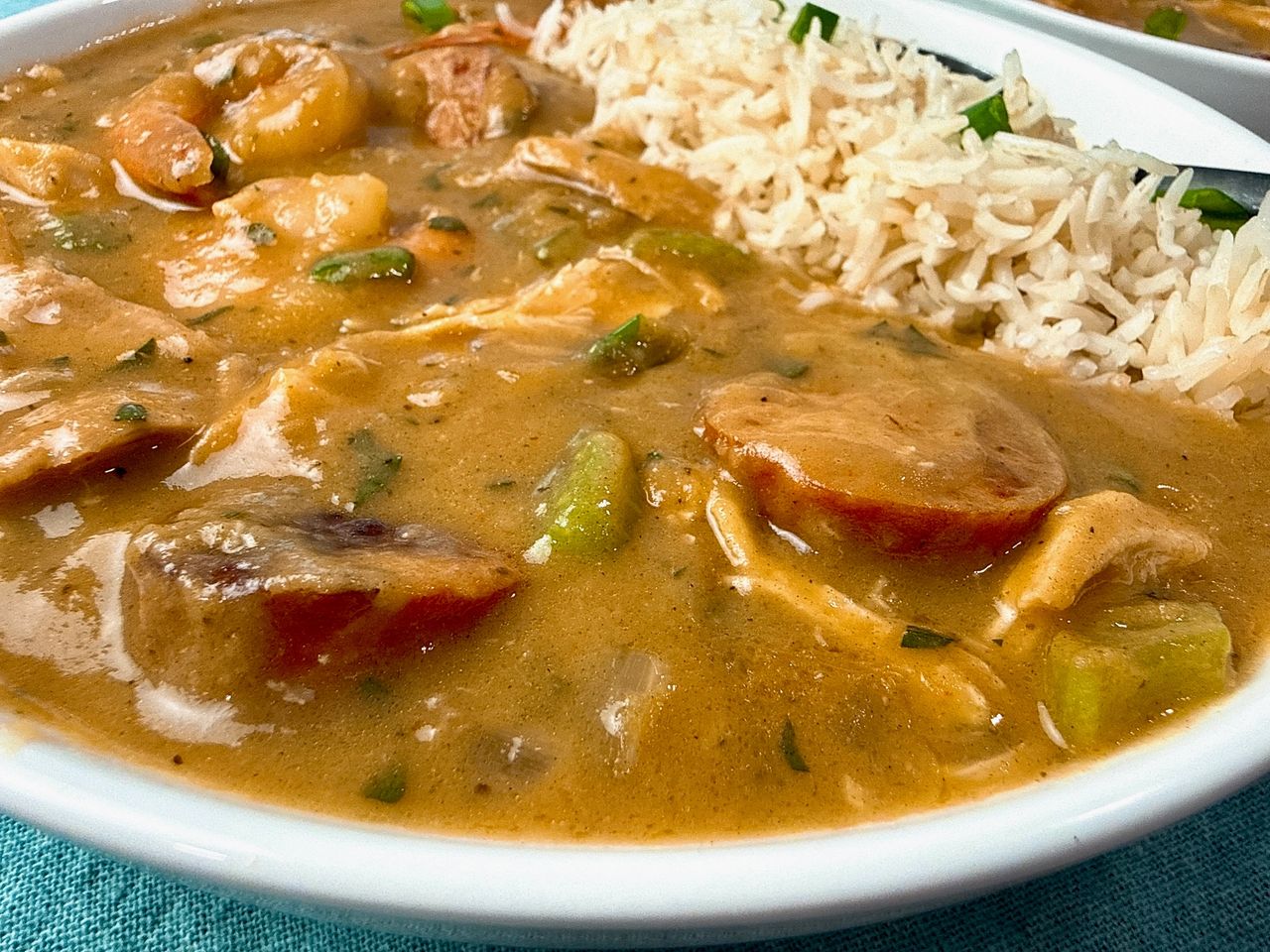 Cajun gumbo and rice in a white bowl with a black spoon
