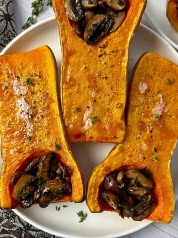 butternut squash stuffed with mushrooms on a white plate