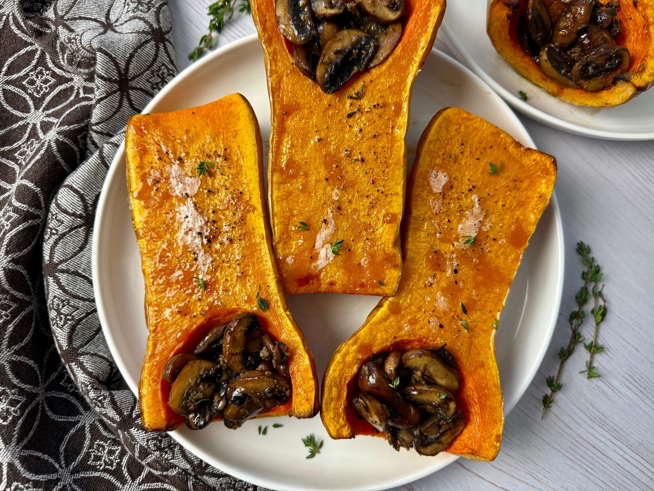 Roasted Butternut Squash with Sautéed Mushrooms butternut squash stuffed with mushrooms on a white plate