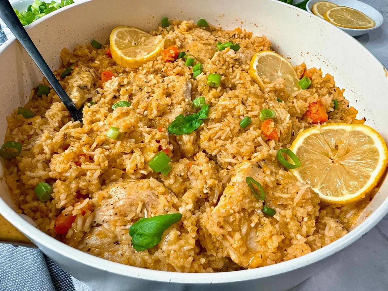 chicken and rice in a white saucepan with lemon garnish