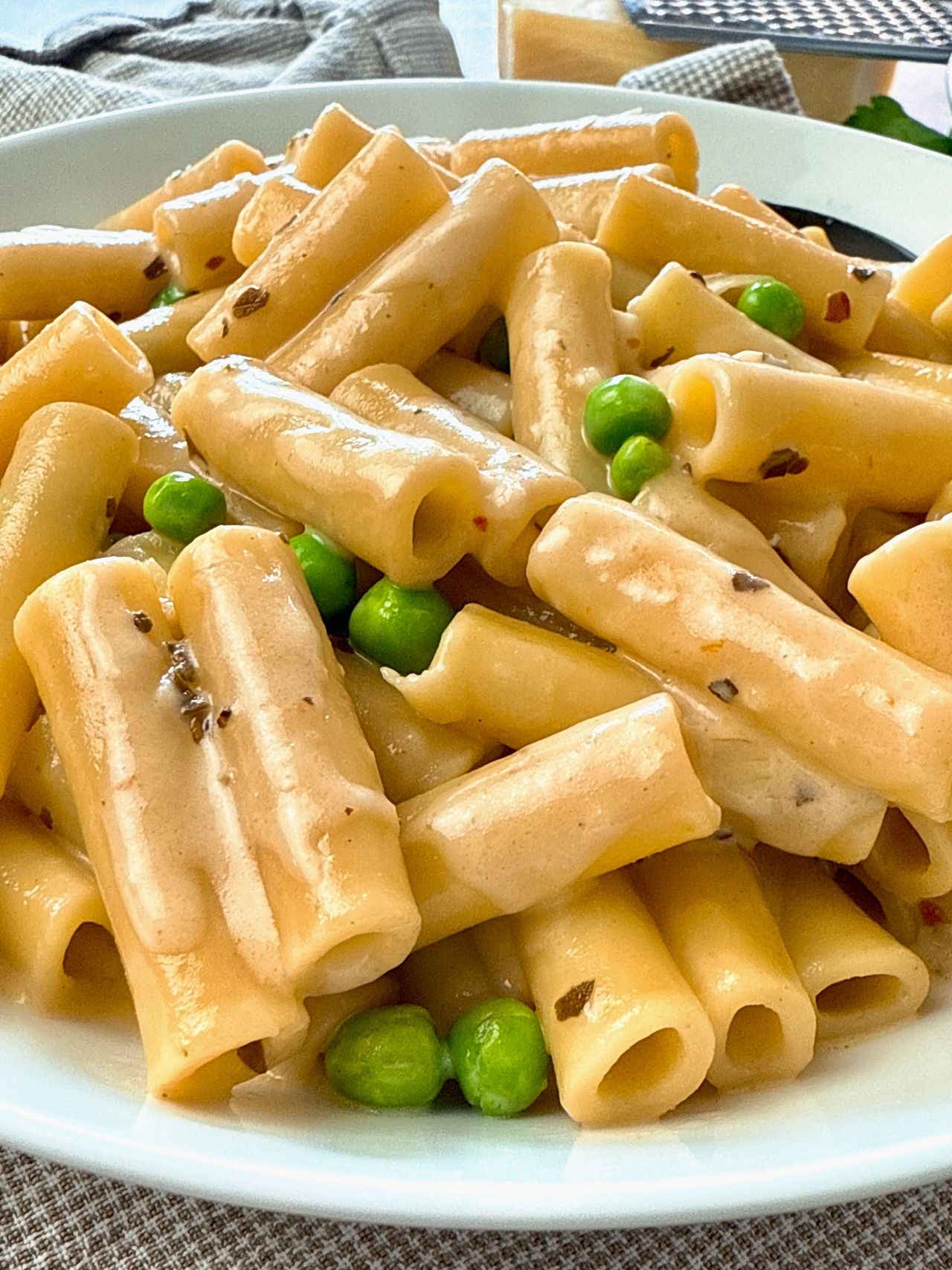 pasta and peas in a cream sauce in a white bowl