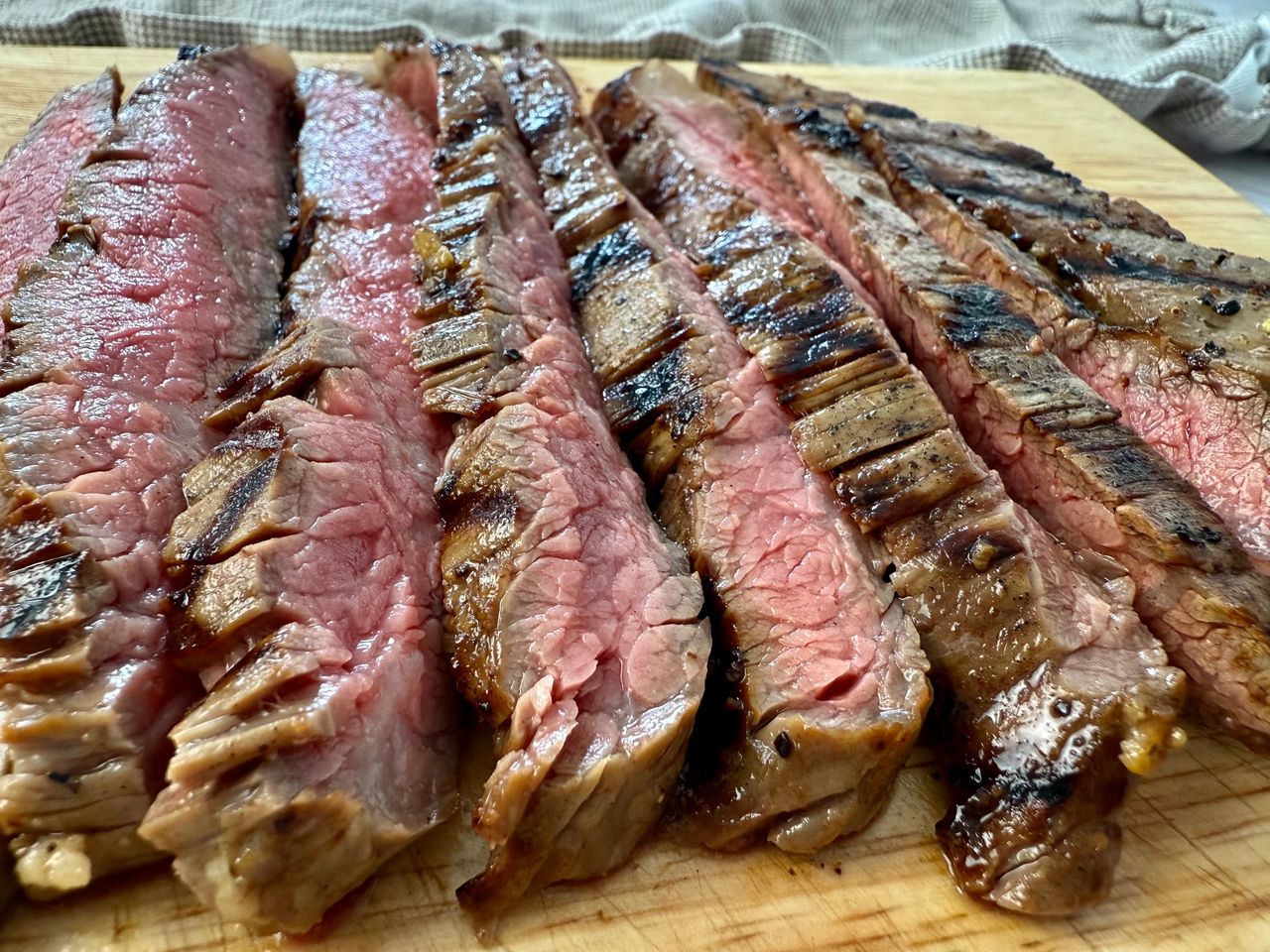 Grilled Flank Steak grilled flank steak slices on a wooden cutting board