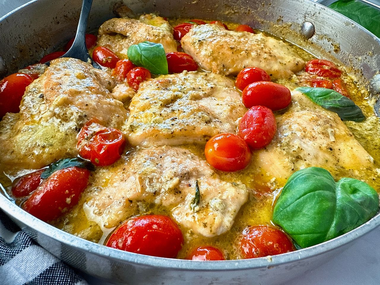 chicken and grape tomatoes with pesto in a silver pan