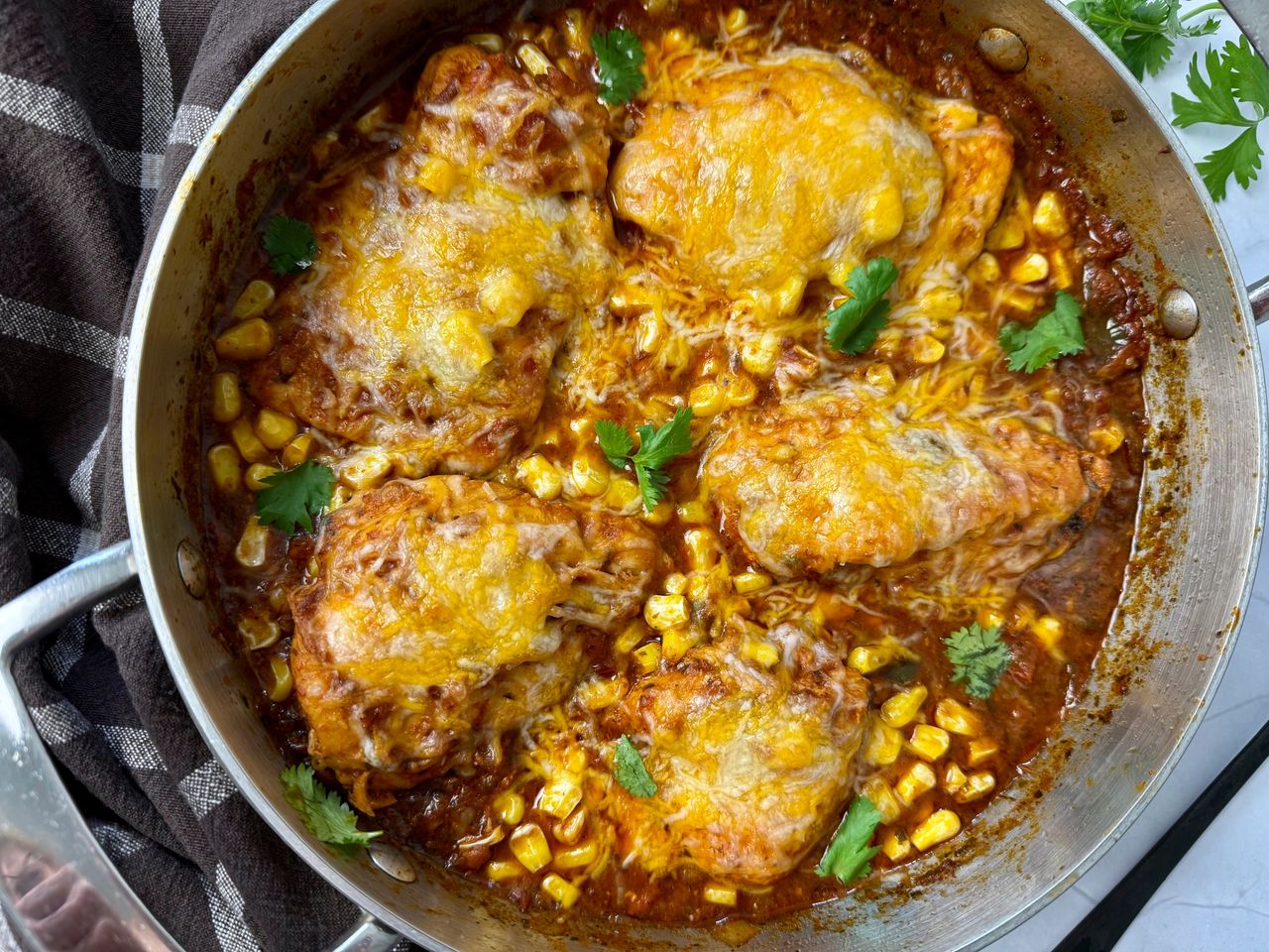 salsa chicken with cheese in a silver pan with a black spoon