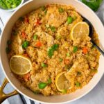 chicken and rice in a white saucepan with lemon garnish