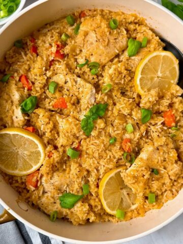 chicken and rice in a white saucepan with lemon garnish