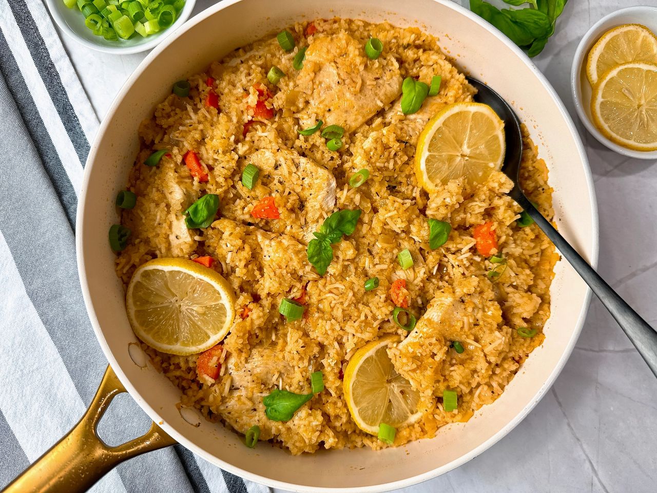 chicken and rice in a white saucepan with lemon garnish