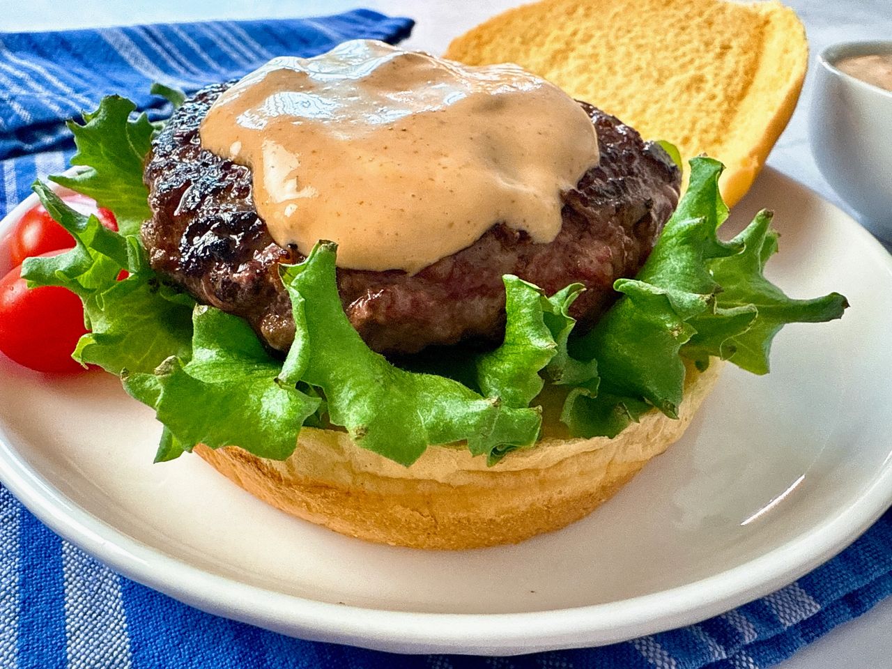 burger on a bun with lettuce and spicy sauce