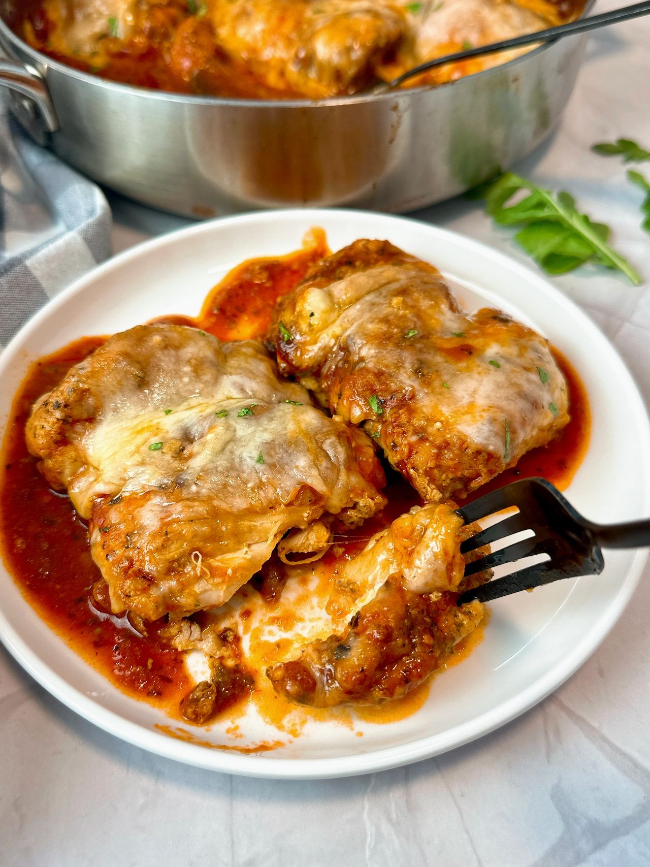 chicken thighs and marinara sauce with cheese in a pan