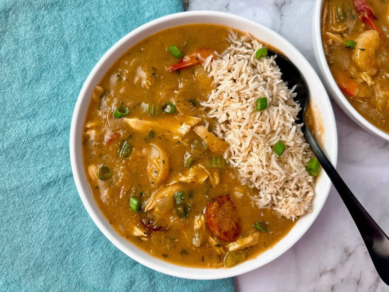 Cajun gumbo and rice in a white bowl with a black spoon