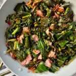 collard greens and ham in a white skillet