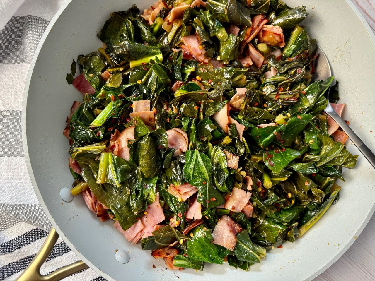 Sautéed Collard Greens collard greens and ham in a white skillet