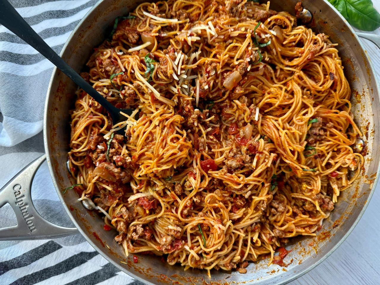 pasta bolognese in a silver pan with a black spoon