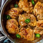 chicken thighs and jalapeno peppers in a silver pan