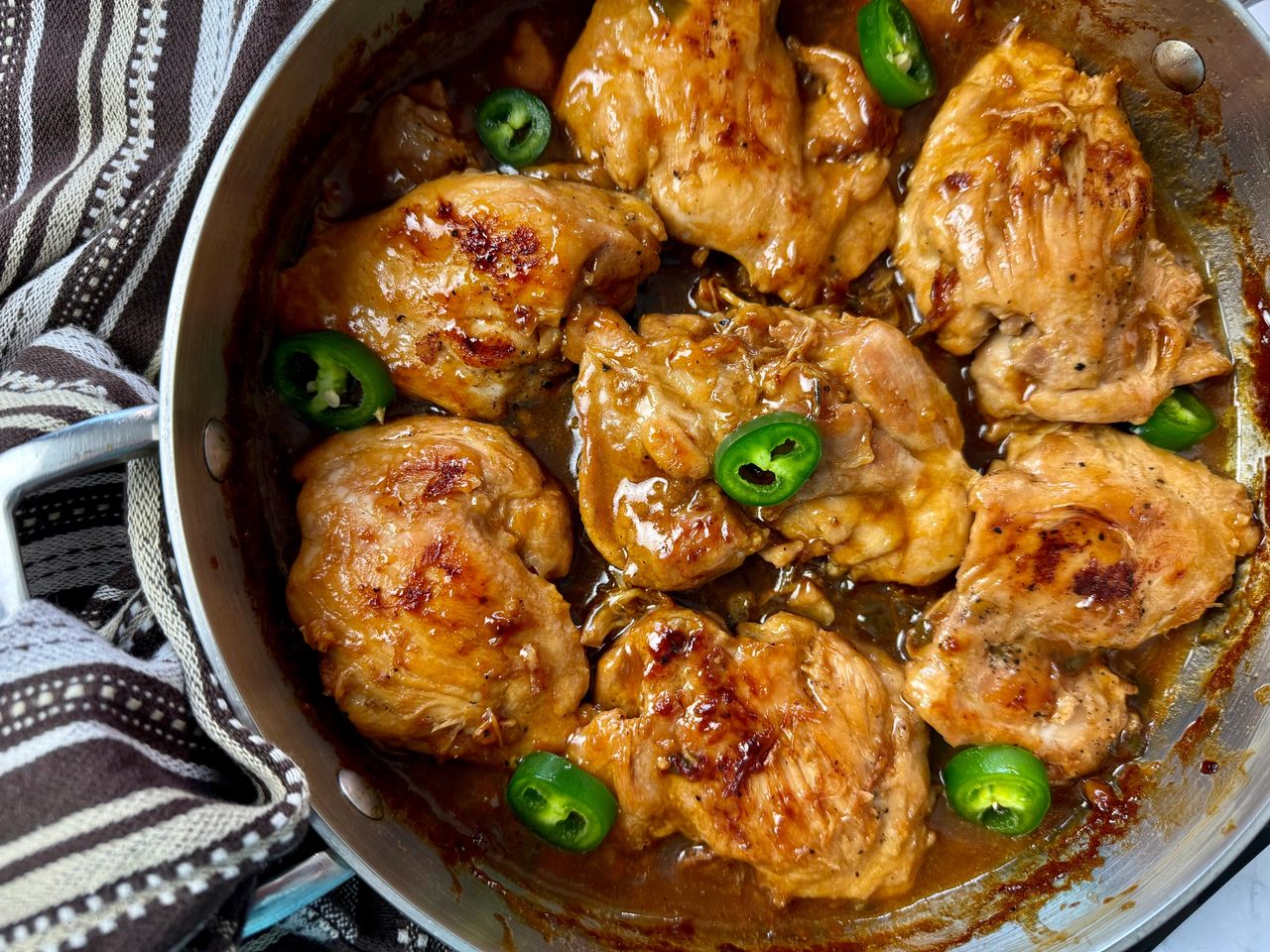 Spicy Jalapeno Chicken chicken thighs and jalapeno peppers in a silver pan