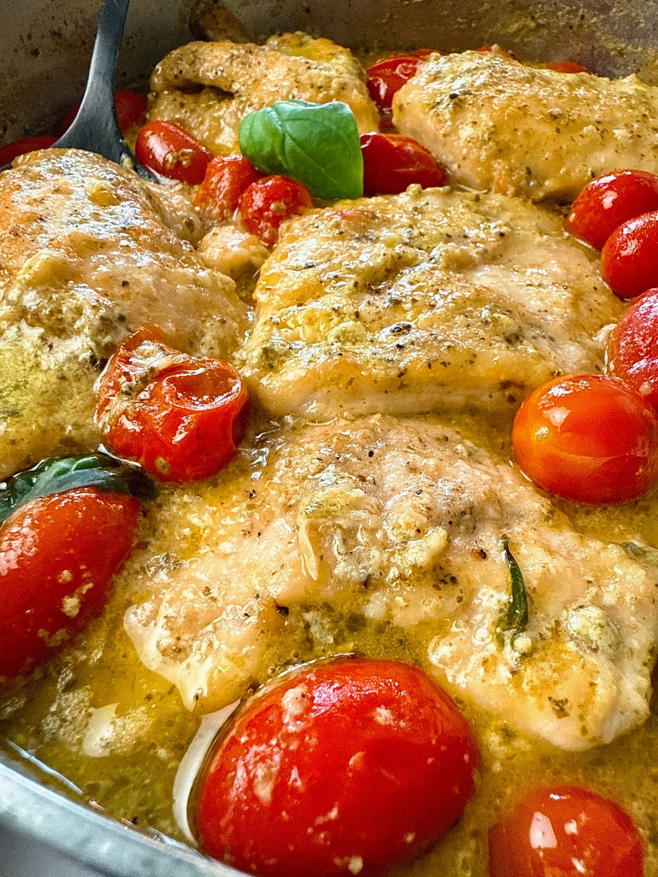 chicken and grape tomatoes with pesto in a silver pan